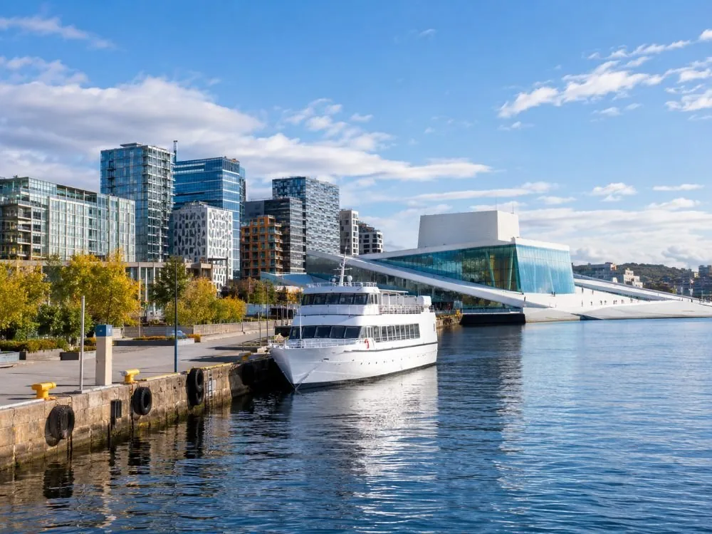 Langkaia, der separate Kai auf der Bjørvika-Seite in der Nähe der Oper und des Hauptbahnhofes, mit einem weißen Fahrgastschiff an der Seite und den neueren Türmen der Stadt, die sich hinter der Uferpromenade erheben.